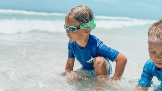 playing on beach with toys wearing Frogglez swim goggles with UV protection during a fun day by the ocean