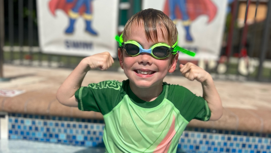 Boy in pool flexing muscles in Green frogz Frogglez kids swim goggles for kids 3-10