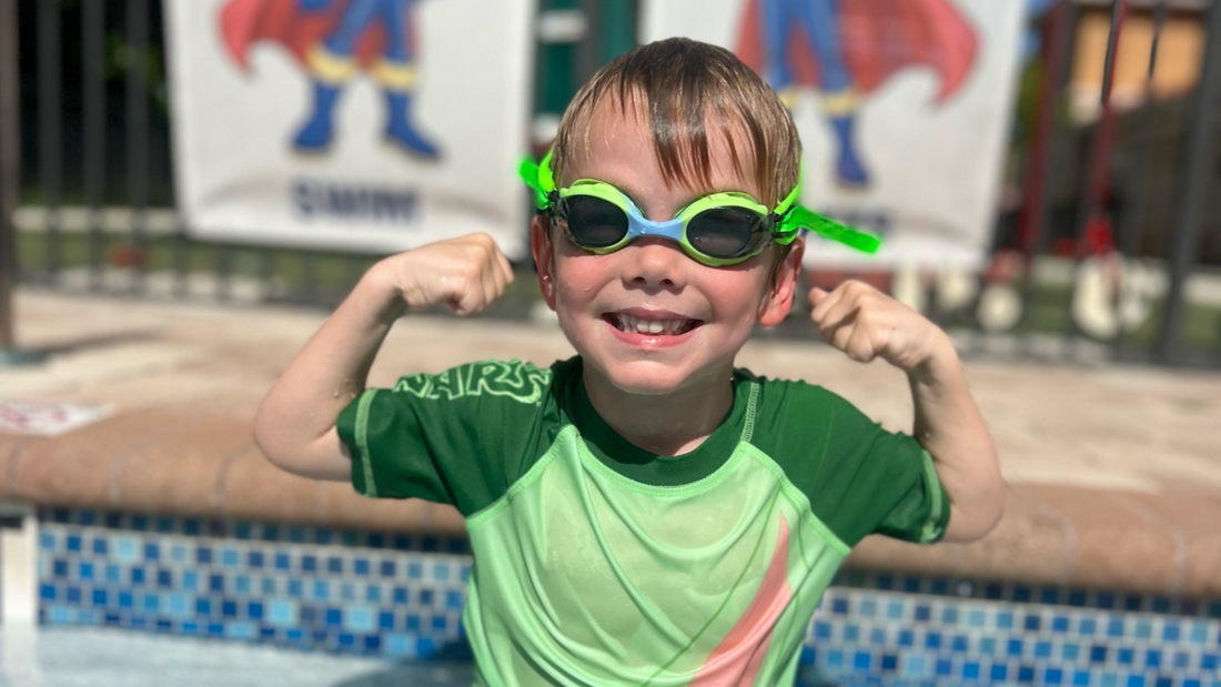 boy smiling at swim lessons giving muscle biceps wearing frogglez goggle best swim goggles for kids