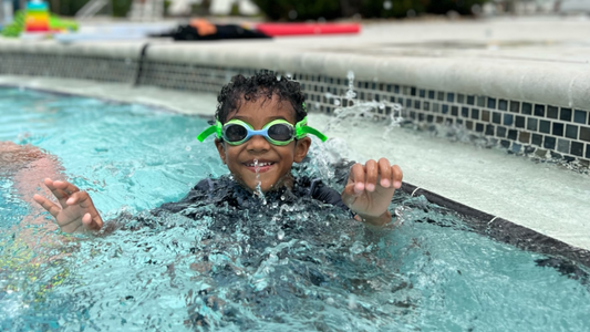 swim student up out of the pool while the student is having fun in his swim lesson wearing Frogglez Kids Swim Goggles.