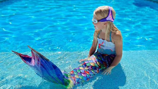 Girl sitting on swimming pool steps wearing Purple Frogglez swim goggles. Frogglez comfortable neoprene strap stretches and won't pull hair. Best swim goggles for boys. Best swim goggles for girls.
